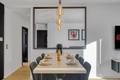 a dining room with a table with chairs and a light fixture at 3 chambres Modern - 2 min du Palais - Climatisé - Calme in Cannes