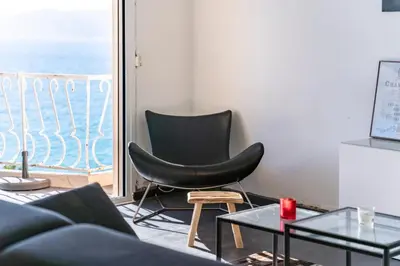 a living room with a black chair and a window at Wonderful 2 bedroom apartment with sea view in Cannes