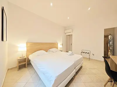 a bedroom with a large white bed and a desk at Viva Riviera 11 rue Commandant André in Cannes