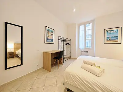 a bedroom with a bed and a desk and a mirror at Viva Riviera 11 rue Commandant André in Cannes