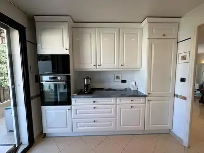 a kitchen with white cabinets and a black appliance at A003-Magnifique appartement proche du centre de Cannes in Cannes