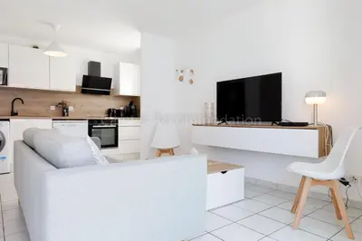 a white living room with a white couch and a tv at Palazzio RE in Cannes