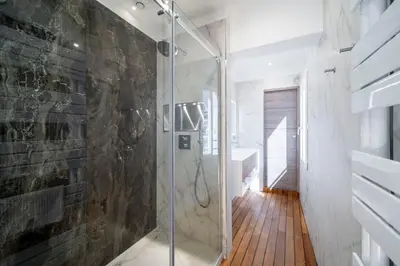 a glass shower in a bathroom with a stone wall at REF 1926 - Cannes Center - Sea view apartment for rent in Cannes