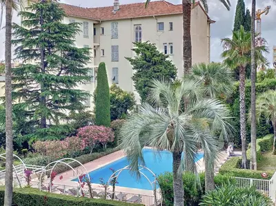 a building with a palm tree and a swimming pool at Cannes - 3 pieces a 15mn Palais in Cannes