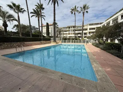 a large swimming pool with palm trees and a building at Cannes - 3 pieces a 15mn Palais in Cannes