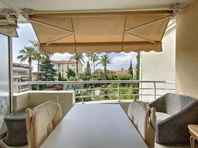 a balcony with a table and chairs and palm trees at Cannes - 3 pieces a 15mn Palais in Cannes