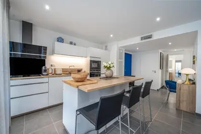 a kitchen with white cabinets and a island with chairs at C035-Cannes Centre appartement 3 pièces avec parking in Cannes