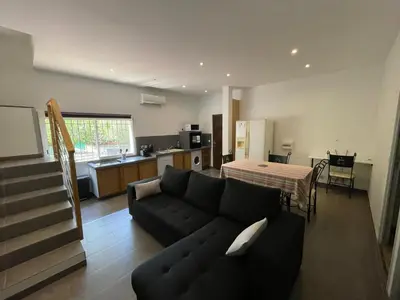 a living room with a black couch and a kitchen at Holiday Home l'Angelet in Vallauris
