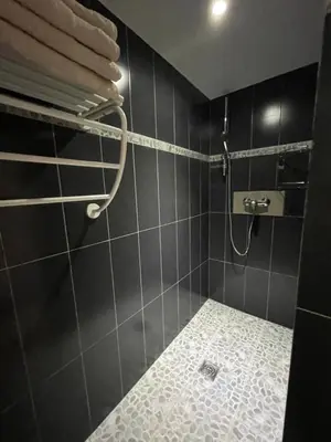 a black tiled bathroom with a shower with a towel rack at Holiday Home l'Angelet in Vallauris