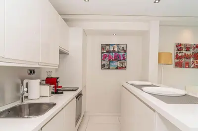 a white kitchen with a sink and white cabinets at Croisette 1 mn 2 BR w/ terrace Olam Properties in Cannes
