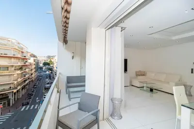 a room with a balcony with a couch and a table at Croisette 1 mn 2 BR w/ terrace Olam Properties in Cannes