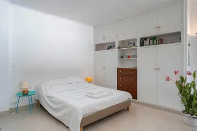 a white bedroom with a bed and white cabinets at Beautiful studio with great sea view in Cannes