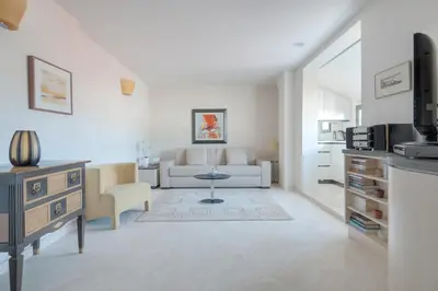 a white living room with a couch and a tv at Wonderful studio heart of Cannes!! in Cannes