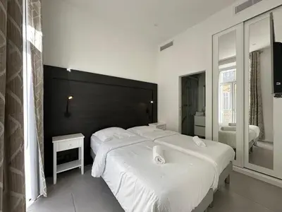 a bedroom with two white beds and a black headboard at B080- À l'étroit à l'hôtel Bienvenue chez nous in Cannes