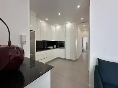 a kitchen with white cabinets and a blue couch at B080- À l'étroit à l'hôtel Bienvenue chez nous in Cannes