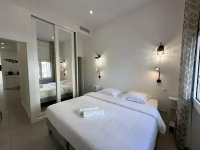 a bedroom with a large white bed and a mirror at B080- À l'étroit à l'hôtel Bienvenue chez nous in Cannes