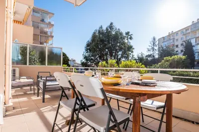 a patio with a wooden table and chairs on a balcony at Bright 2bedroom apartment 15min walk to the Palais in Cannes