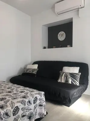a black couch in a room with a clock on the wall at Studio cosy en plein centre-ville in Cannes