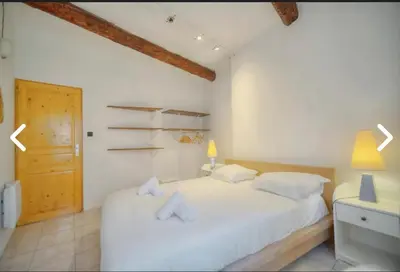 a bedroom with a white bed and a wooden door at Appartement Canne 1 chambre - 12RP in Cannes