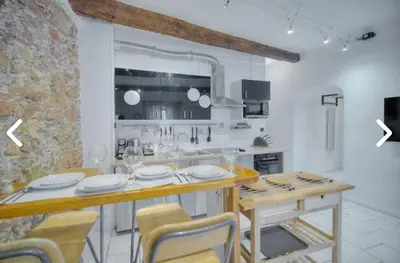 a white kitchen with a wooden table and chairs at Appartement Canne 1 chambre - 12RP in Cannes