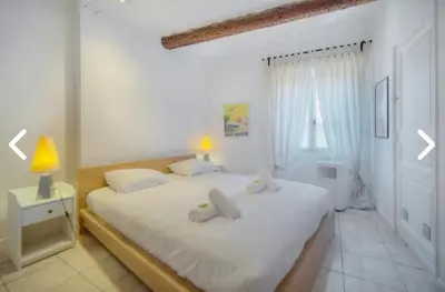 a white bedroom with a bed and a window at Appartement Canne 1 chambre - 12RP in Cannes