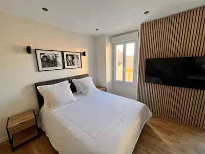 a bedroom with a white bed and a flat screen tv at Appartement comme une suite d’hôtel in Cannes