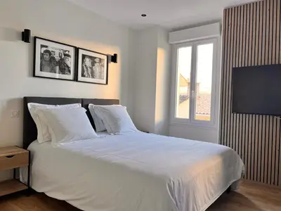 a bedroom with a bed with white sheets and a window at Appartement comme une suite d’hôtel in Cannes