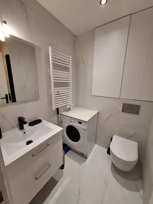 a white bathroom with a sink and a washing machine at Appartement comme une suite d’hôtel in Cannes