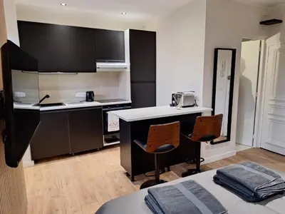 a small kitchen with two chairs and a counter at Appartement comme une suite d’hôtel in Cannes