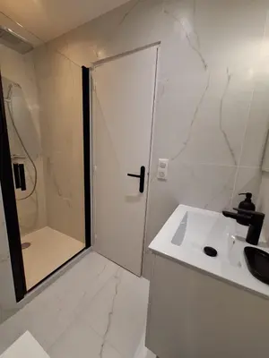 a white bathroom with a shower and a sink at Appartement comme une suite d’hôtel in Cannes