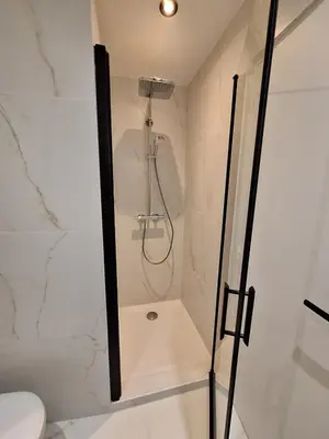 a shower in a white bathroom with a glass door at Appartement comme une suite d’hôtel in Cannes