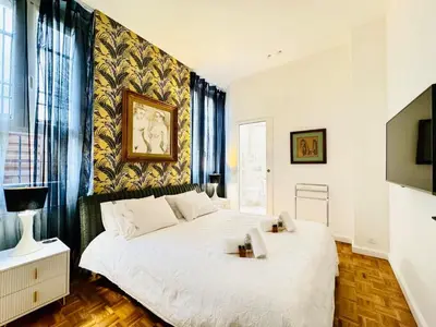a bedroom with a large white bed and a tv at Le Guynemer - Appartement Beaux Arts Cannes in Cannes