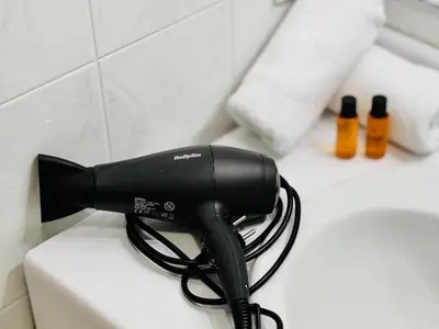 a black hair dryer sitting on top of a sink at Le Jardin Gallieni - Terrasse Cozy in Cannes