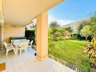 a patio with a table and chairs and a yard at Le Jardin Gallieni - Terrasse Cozy in Cannes