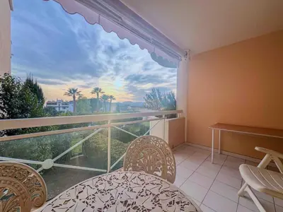 a balcony with a table and chairs and a large window at Terrasse Vue Mer - A quelques minutes de Cannes in Le Cannet