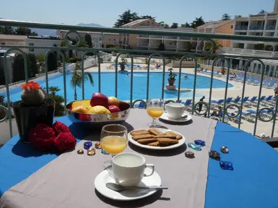 a table with food and drinks and a view of a pool at Cannes vue mer appt 4pers in Cannes