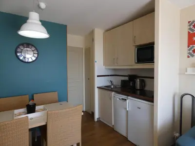 a kitchen with a table and a clock on the wall at Cannes vue mer appt 4pers in Cannes