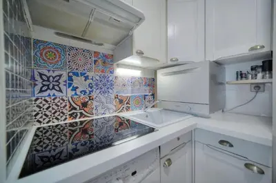 a kitchen with white cabinets and colorful tiles on the wall at One Bed Apt in the center of Cannes - 2198 in Cannes
