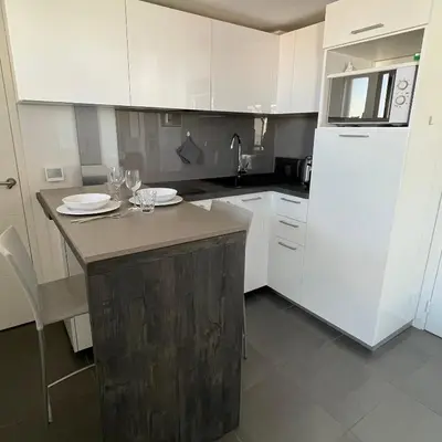 a kitchen with white cabinets and a white refrigerator at Top Floor Secret Garden, Cannes in Cannes
