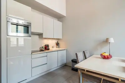 a kitchen with white cabinets and a dining table at Beautiful 2 bedroom in the heart of Cannes in Cannes