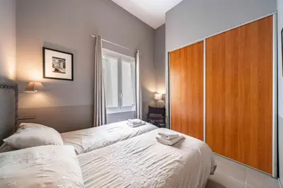 a bedroom with two beds and a wooden cabinet at Beautiful 2 bedroom in the heart of Cannes in Cannes