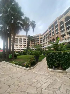 a large building with palm trees in a courtyard at La Perla del Mare in Cannes