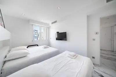 a white bedroom with two beds and a television at Beautiful 3 bedroom close to the Martinez in Cannes