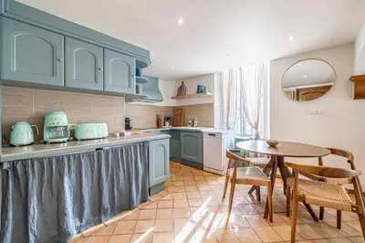 a kitchen with blue cabinets and a table and chairs at Charming apartment heart of Suquet neighborhood in Cannes