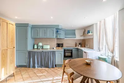 a kitchen with blue cabinets and a wooden table at Charming apartment heart of Suquet neighborhood in Cannes