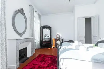 a white bedroom with a bed and a mirror at 77 Avenue de Grasse in Cannes