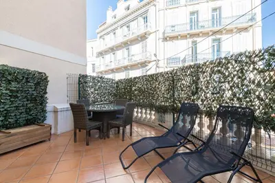 a balcony with chairs and a table and a building at 77 Avenue de Grasse in Cannes