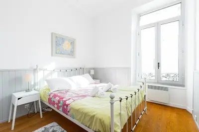a white bedroom with a bed and a window at 77 Avenue de Grasse in Cannes