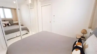a white bedroom with a bed and a mirror at Le Palais Des Iles in Cannes