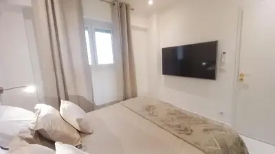 a white room with a bed and a flat screen tv at Le Palais Des Iles in Cannes